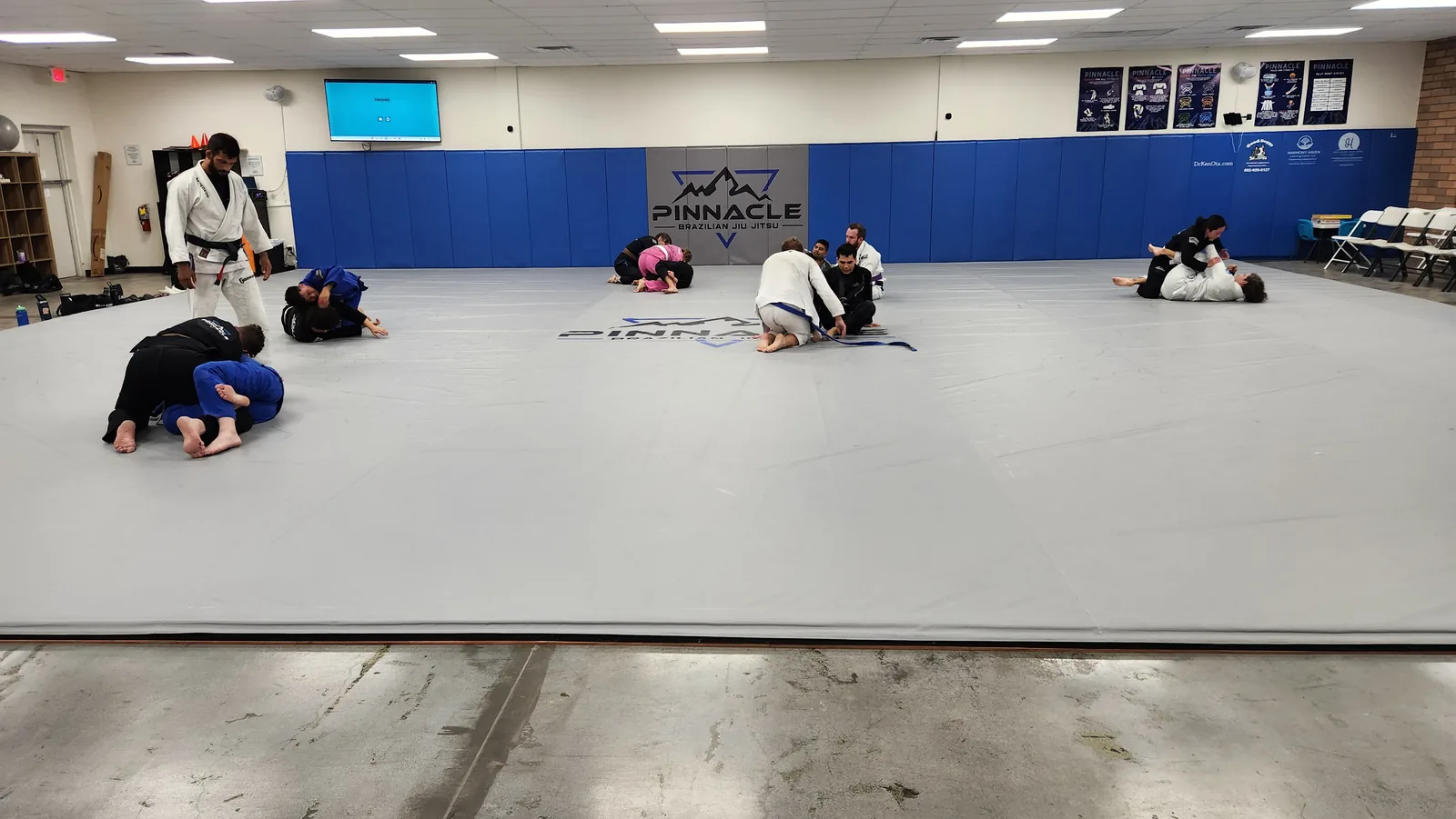 The main training mat at Pinnacle Brazilian Jiu Jitsu with an adult class rolling